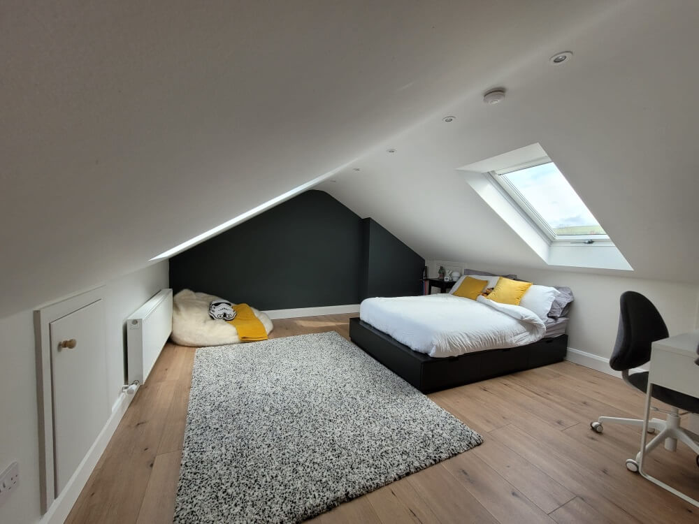 Finished loft room with a sloping ceiling, roof window and dark feature wall
