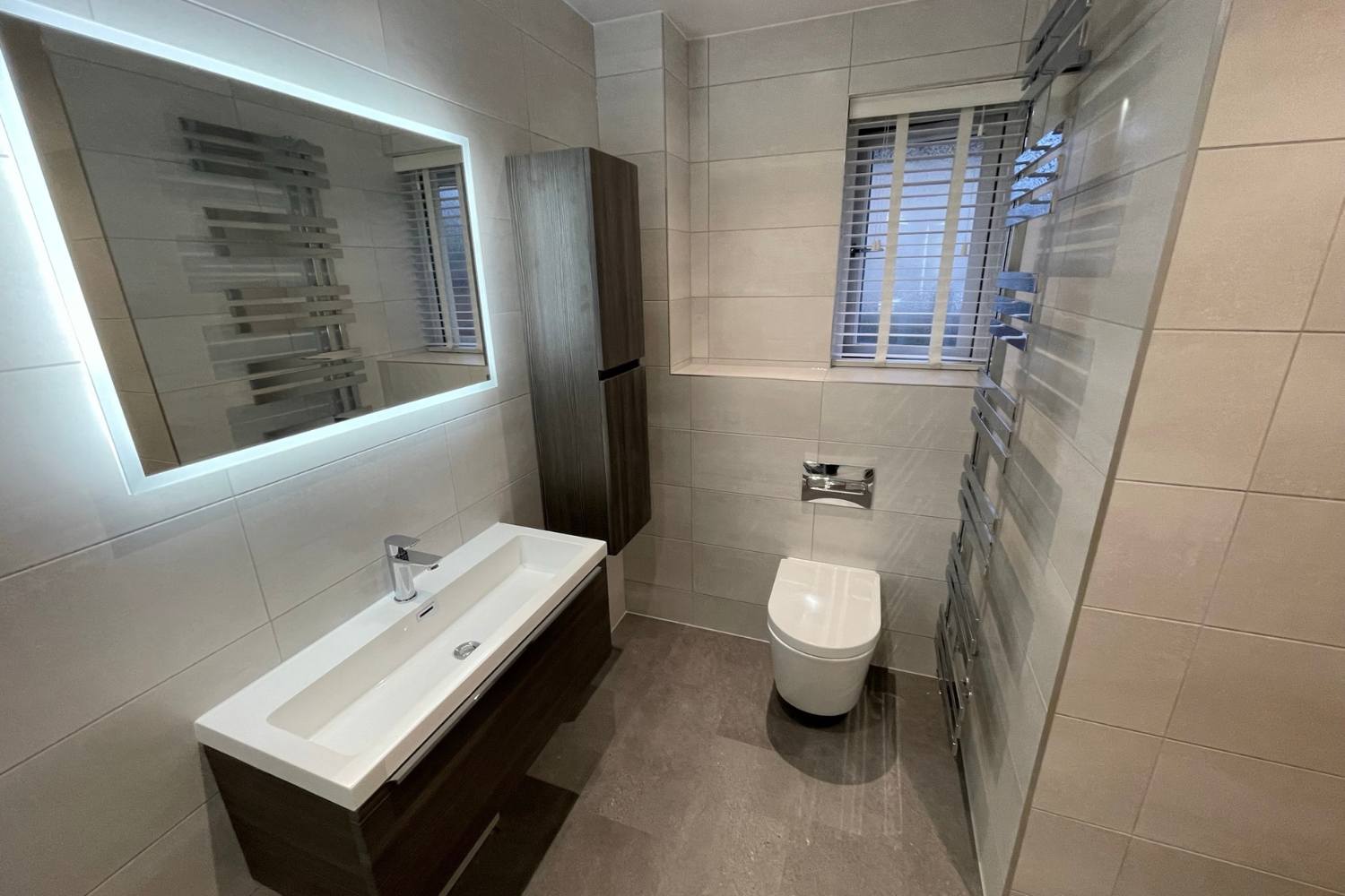Tiled bathroom by Alpha Renovations featuring an illuminated mirror and vanity