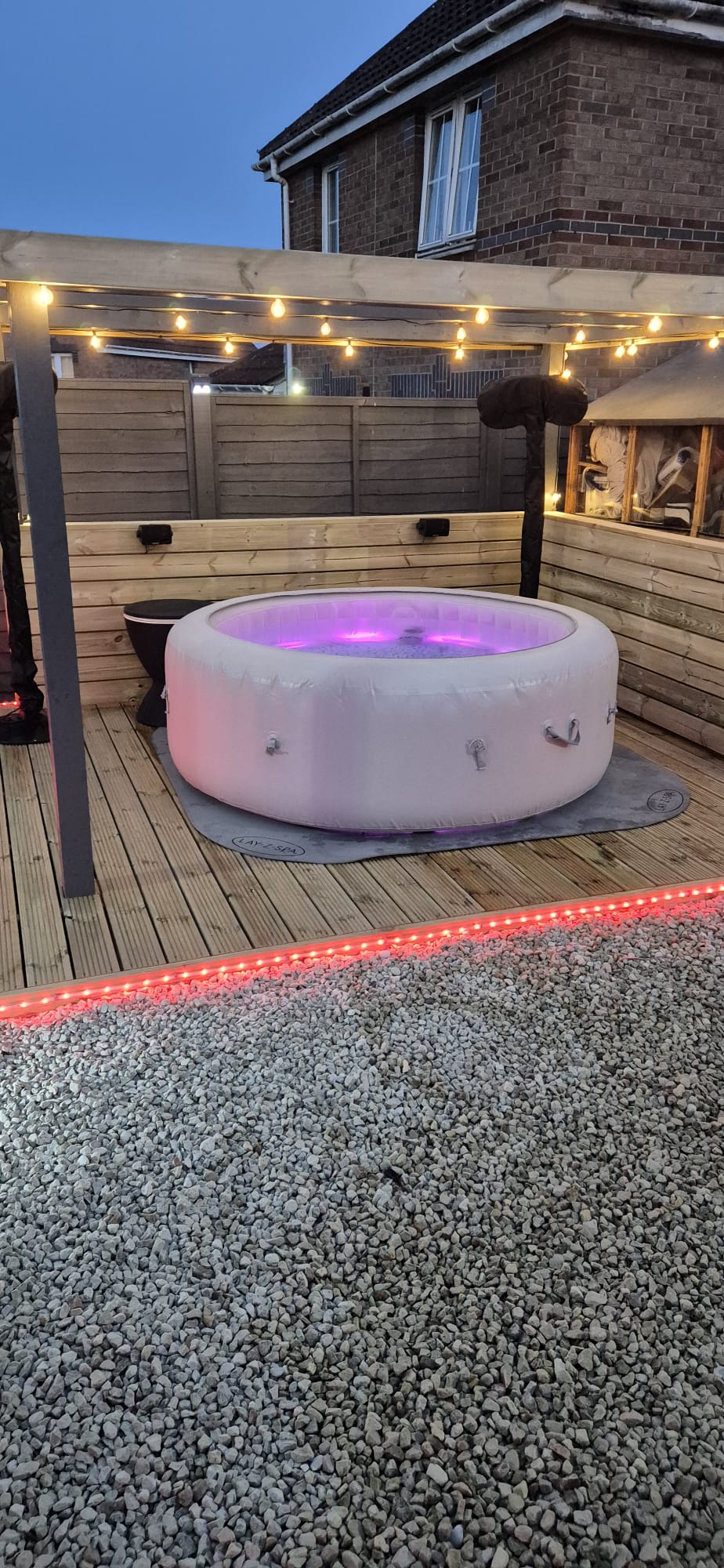 Patio seating area among decking and a gravel garden at dusk