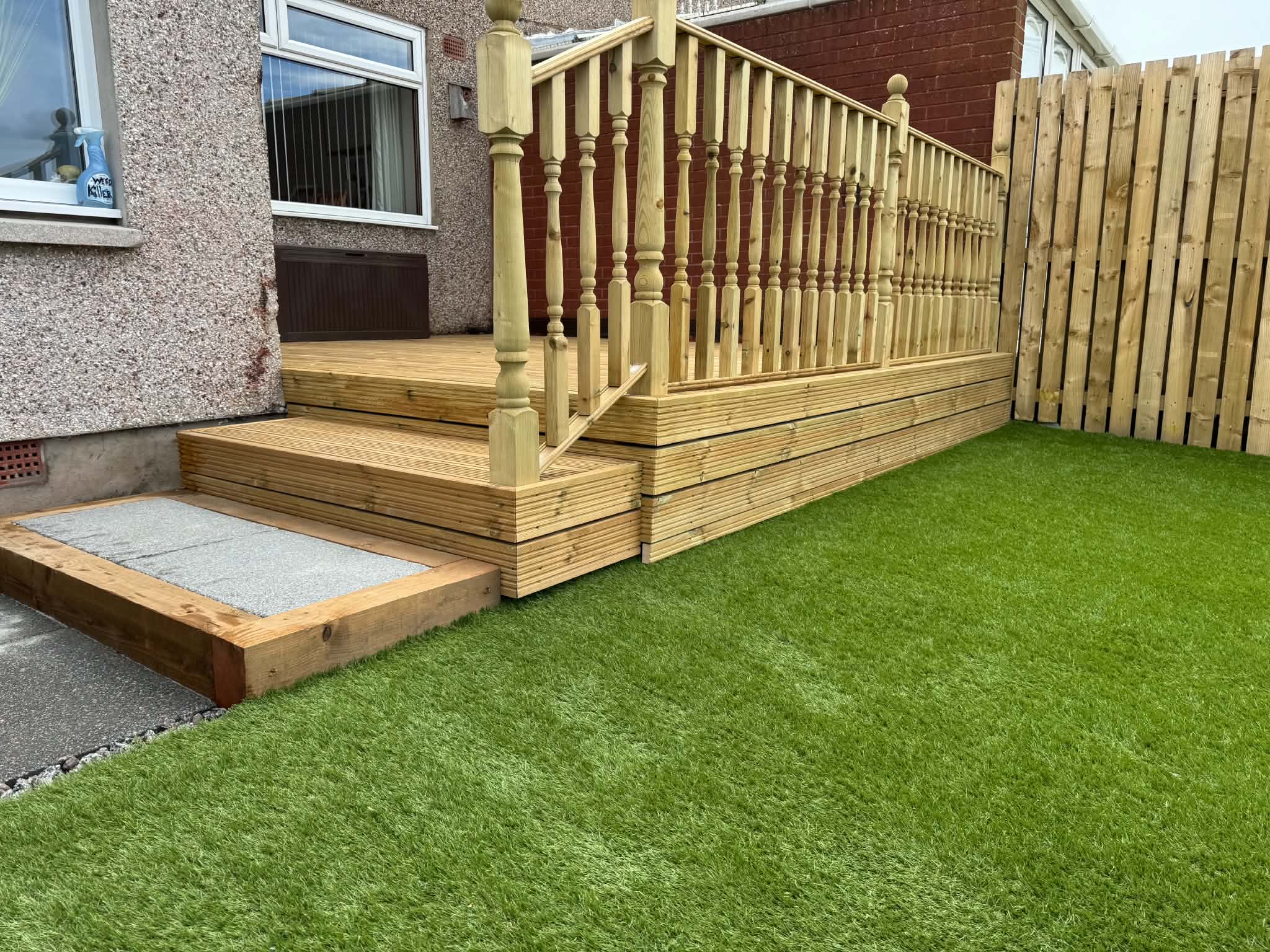 Timber decking steps down to a finished artificial lawn