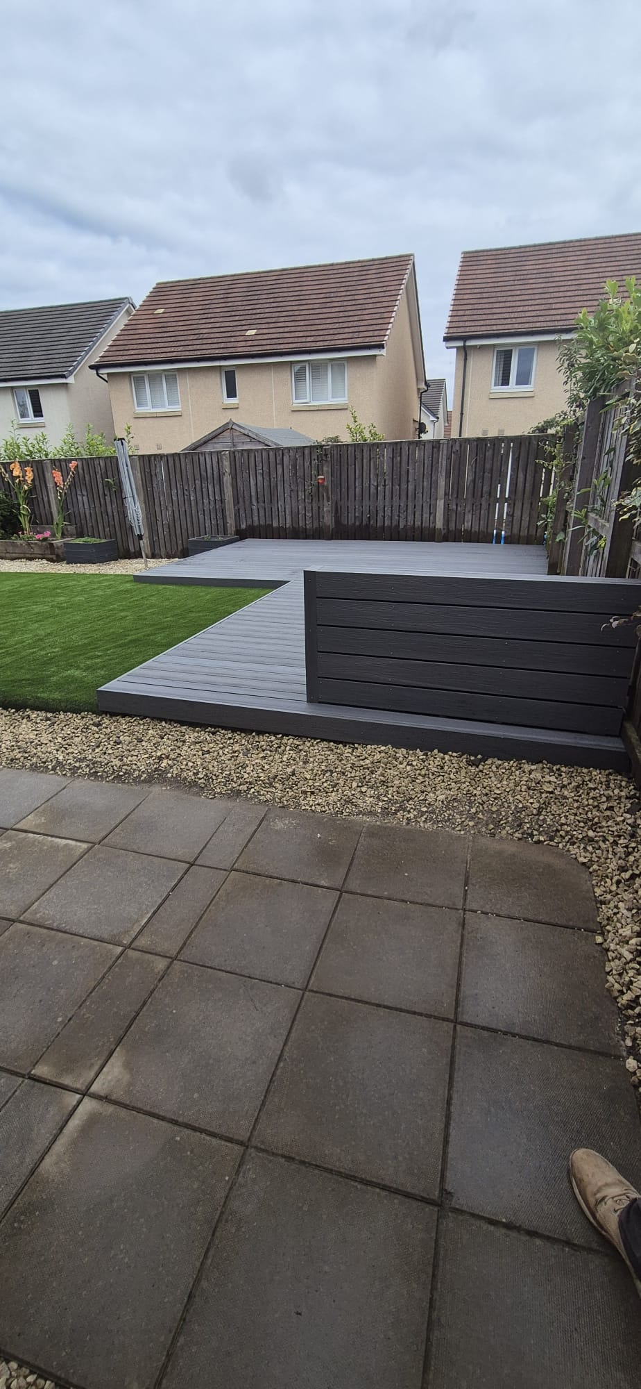 Composite decking with a gravel border beside a lawn