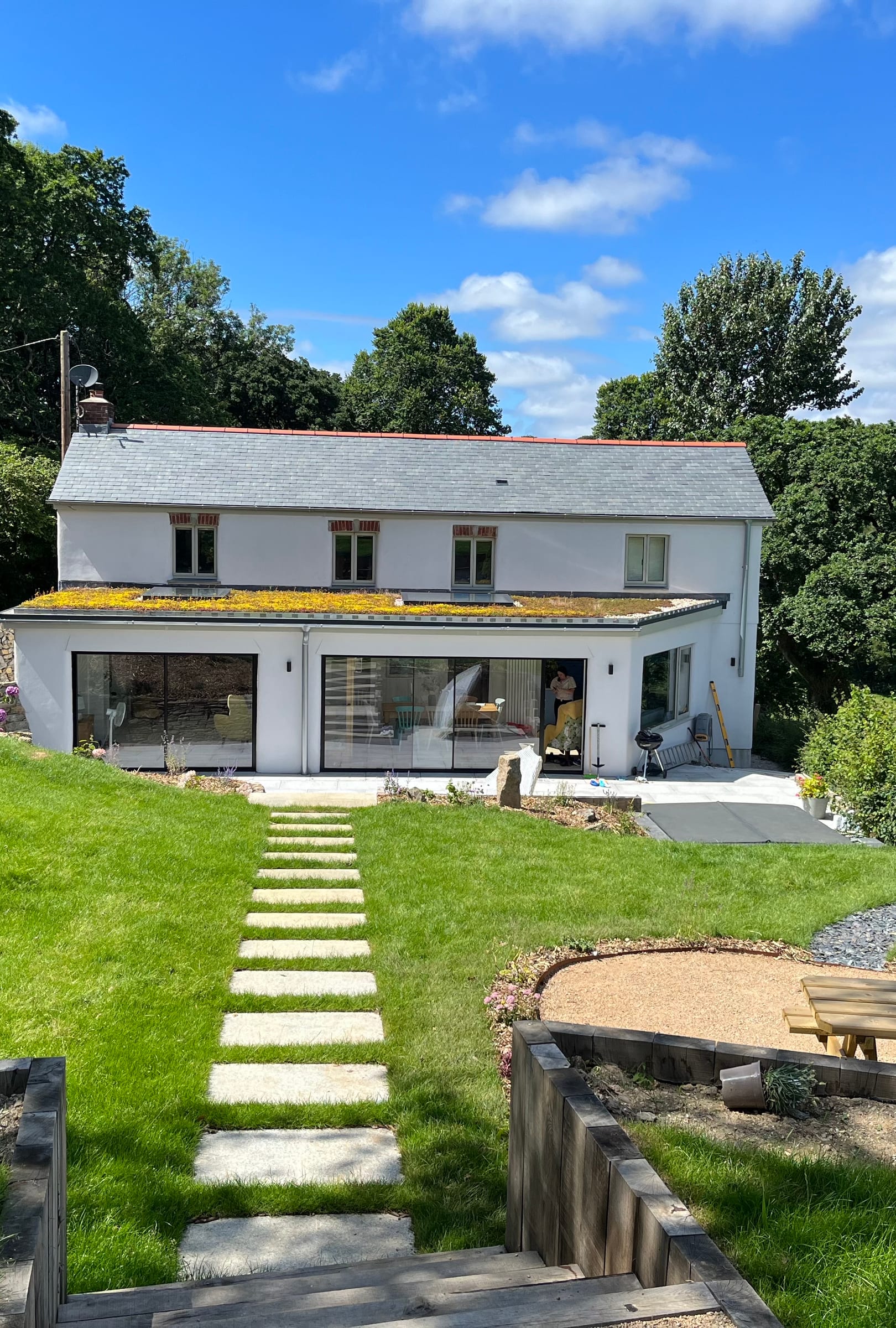 A home with a glazed garden extension built by Mitchell & Andrew Building Services, next to a landscaped lawn