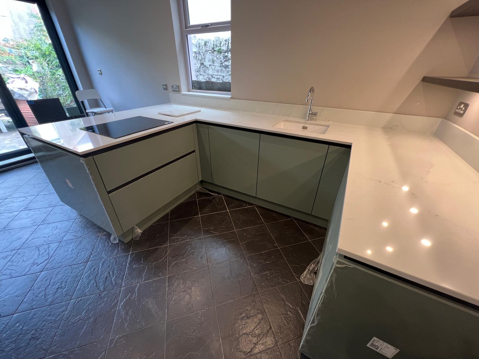 Sage green handleless kitchen and island with quartz worktops, fitted by Truscon
