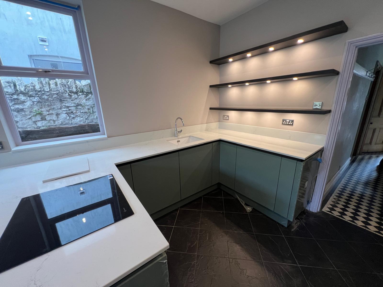 Quartz worktop with undermount sink and lit floating shelves, fitted by Truscon