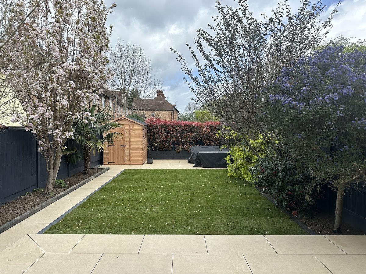 Sandstone patio with artificial turf and a garden shed